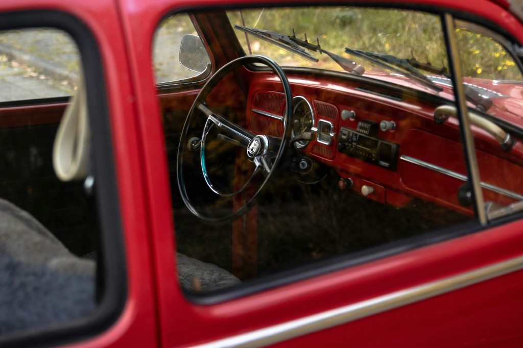 Image is a color photograph of a steering wheel in a vintage car; title card for the new flash fiction, "Rush Hour Ghost," by Fred Muratori.