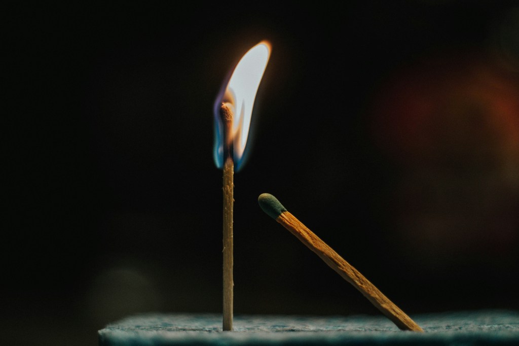 Image is a color photograph of a lit match next to an unlit match; title card for the new flash essay, "Lucky," by Nate Methot.