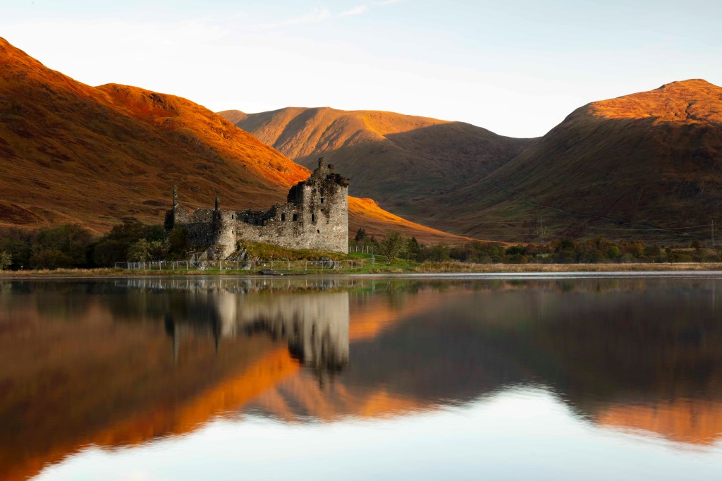 Image is a color photograph of a ruined castle on a lake; title card for the new microessay, "“On the Anniversary of My Mother’s Death,” by Amy L. Bernstein.