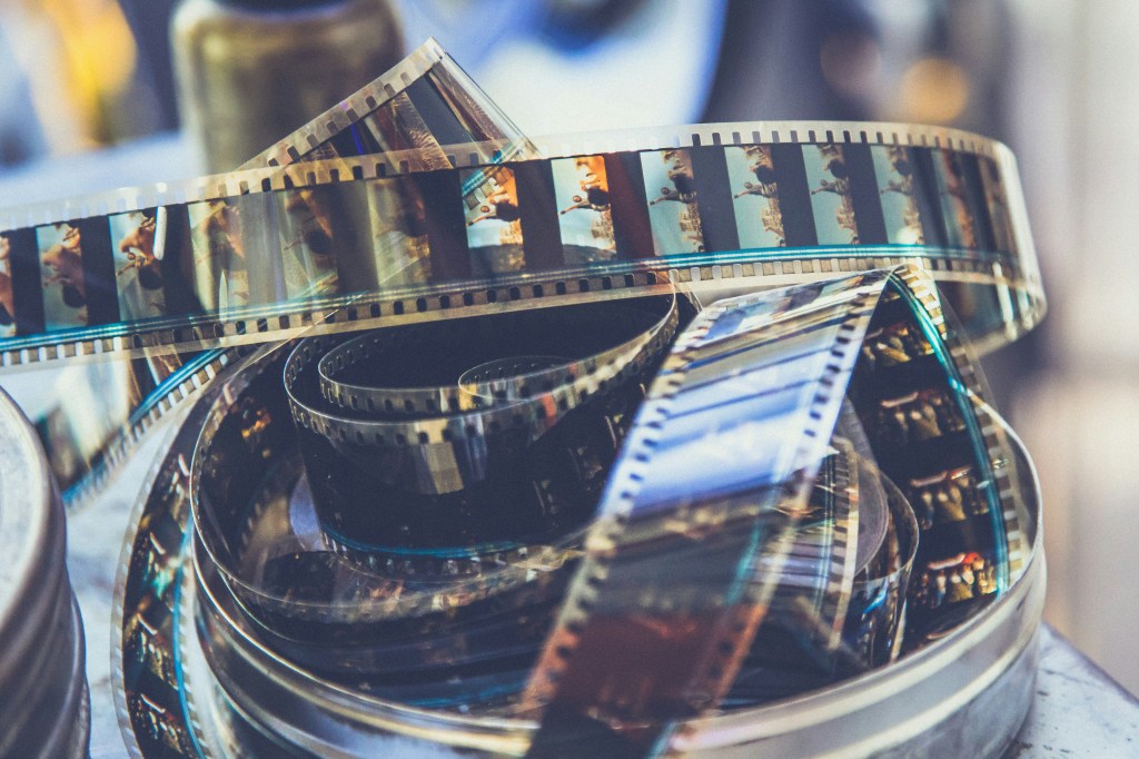 Image is a color photograph of movie film unspooling from a metal cannister; title card for "Director's Cut," a new flash fiction by Kathryn Kulpa.